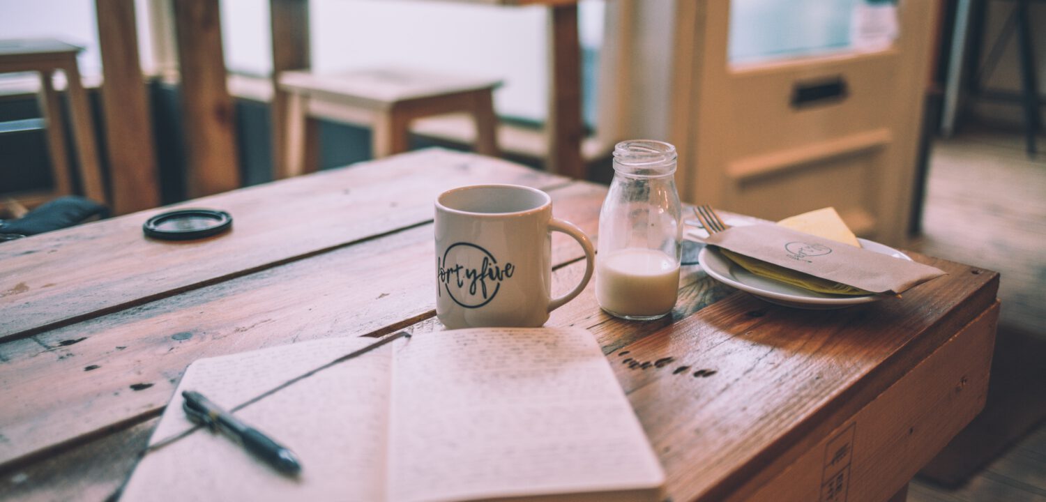 A cup of coffee and a notebook on a table in a café